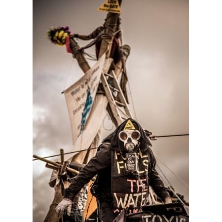 masked activist in front of protest tripod