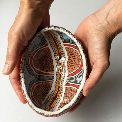 person holding pot with Indigenous pattered glaze