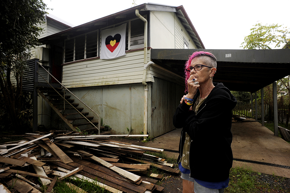 A first nations woman standing in front of her house in South Lismore, that was detroyed in the 2022 flood events. 