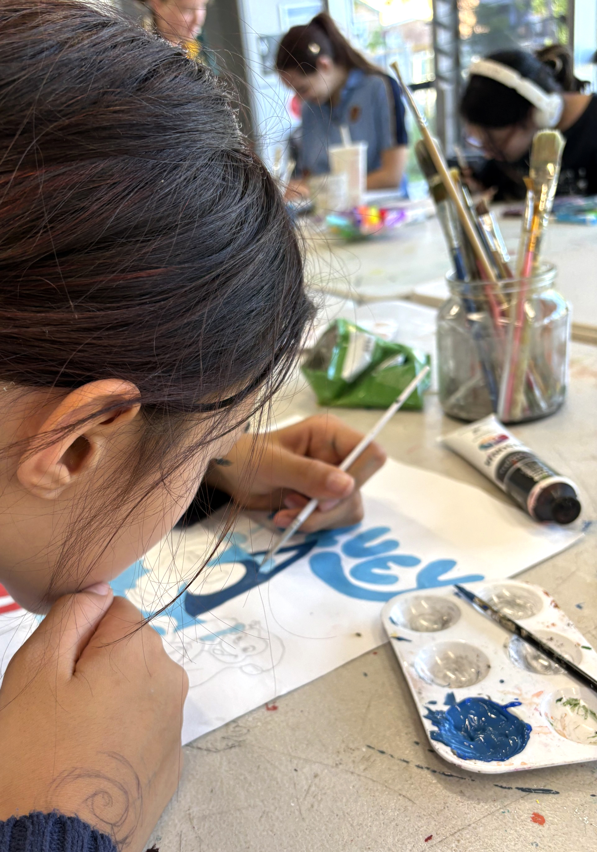 A teen working closely on a painting of Bluey