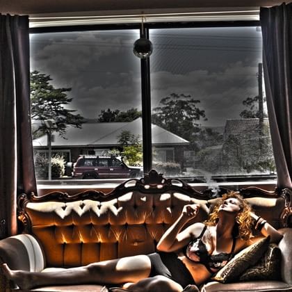 woman reclining on couch in front of window with street scene outside