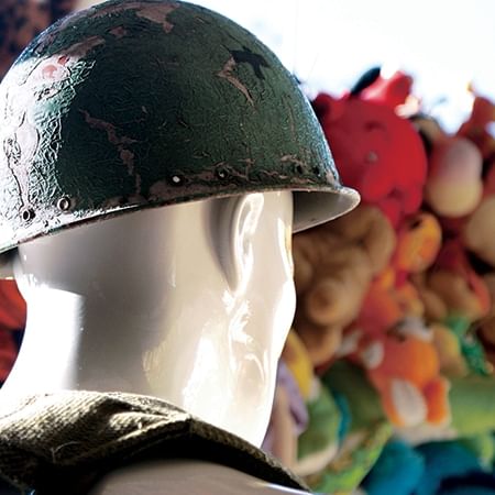 Headshot of statue with hard hat in foreground with stuffed toys in background