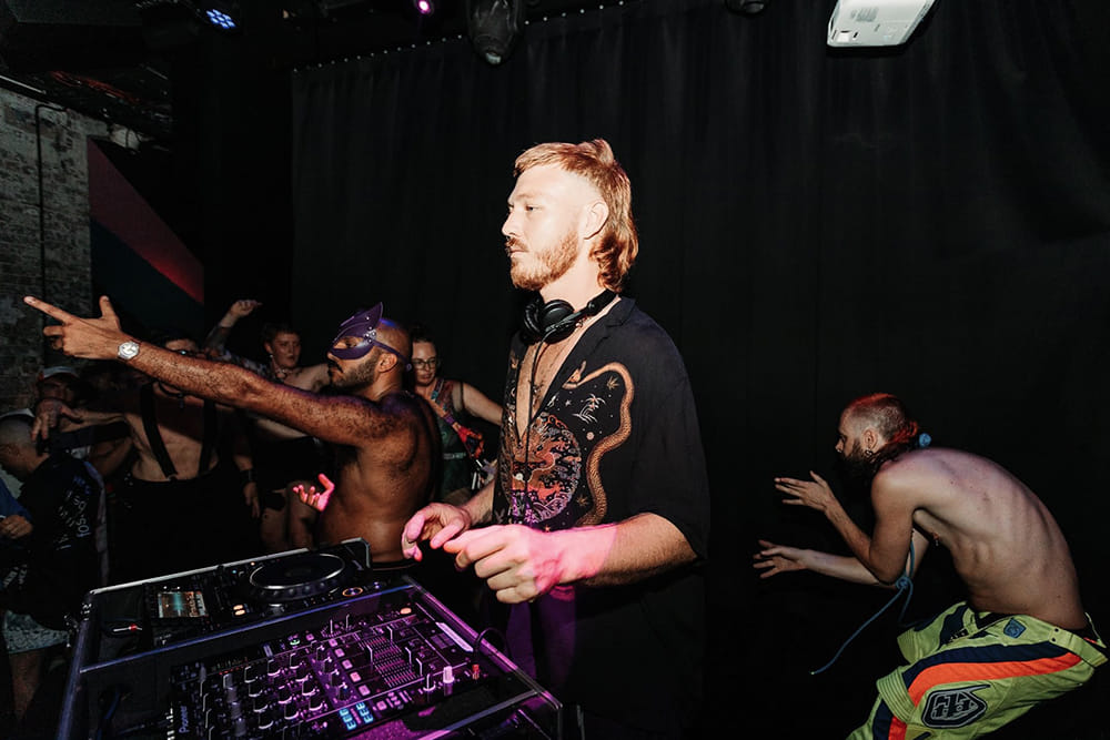 man at mixing desk with crowd behind him