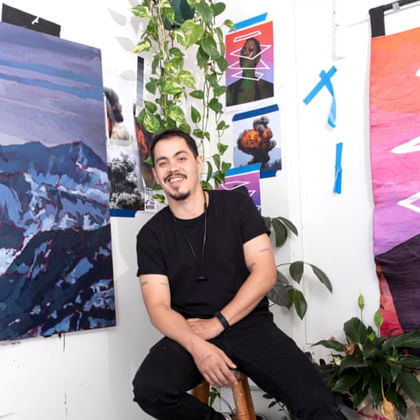 Abdul Abdullah sitting in front of artworks and plants