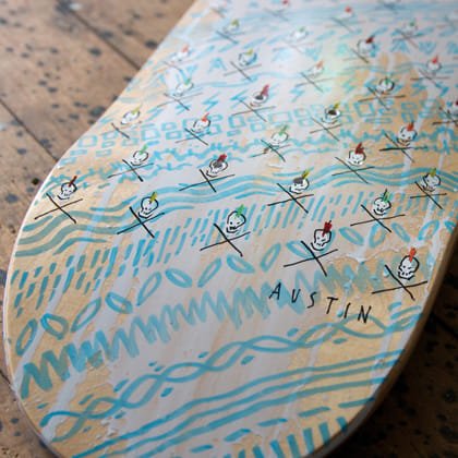 hand ainted skatobard deck with 'punk' skull and crossbones on patterned background