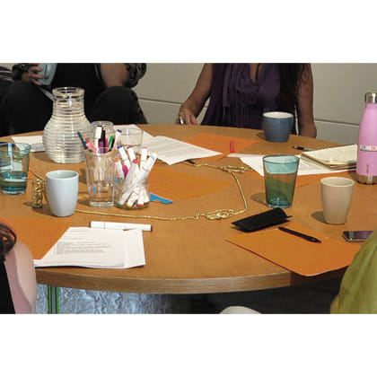 people at table with writing materials and drinking cups