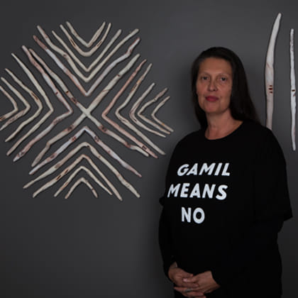 Artist Penny Evans in front of wall art made from ceramic