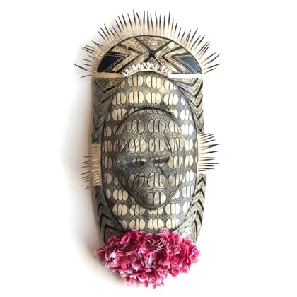 oval shaped ceramic work with relief head shape with patterned glaze over work. There is a bunch of flowes ant the bottom o the piece and decorative echidna quills on the top and side edges.