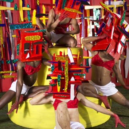 group of people wearing colourful masks and all dressed in white shorts and red bras