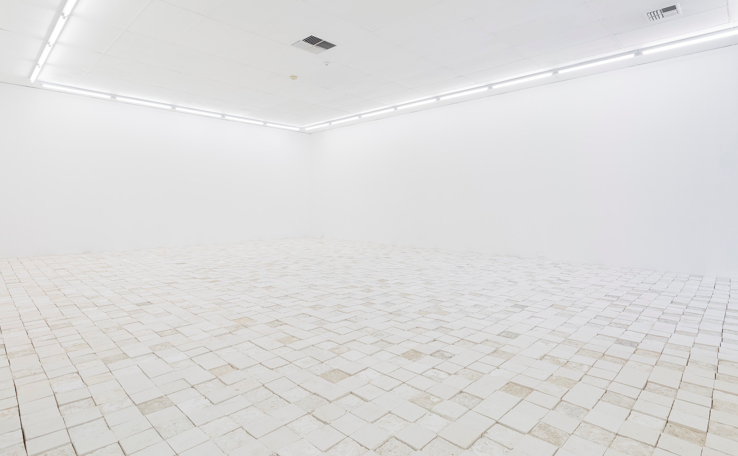 A photo of a gallery with many chalk tiles like pavement on the floor. 
