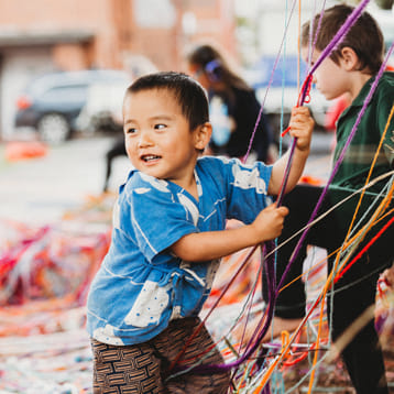 young child playing with coloured strings 