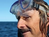 man wearing snorkelling goggles with the sea behind him 