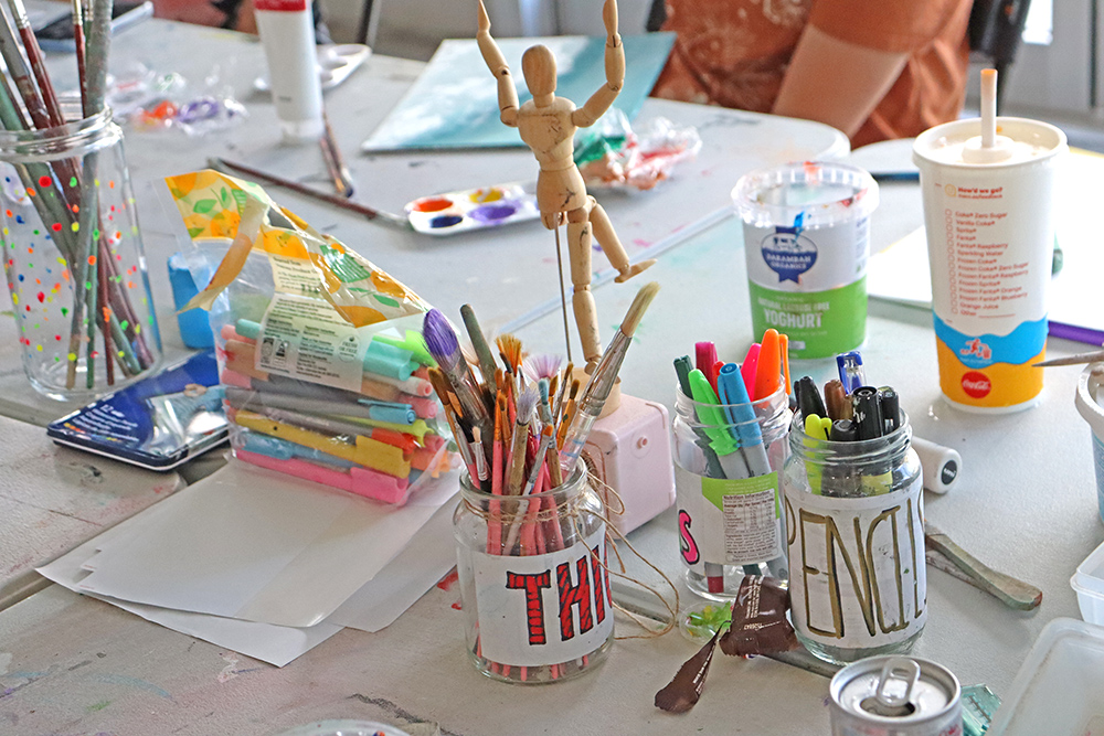 A table with art and craft materials like paints, pencils and paper