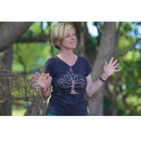 woman talking in front of tree with hands raised 
