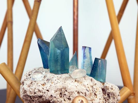 Blue crystals set on piece of stone surrounded by multiple narrow bamboo poles.