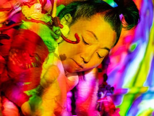 Portait of the artist surrounded by colourful textile forms