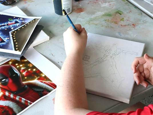 A photo of a kids hands drawing a picture of Spider Man