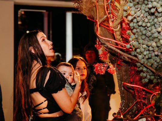 A woman and children looking at a large sculpture