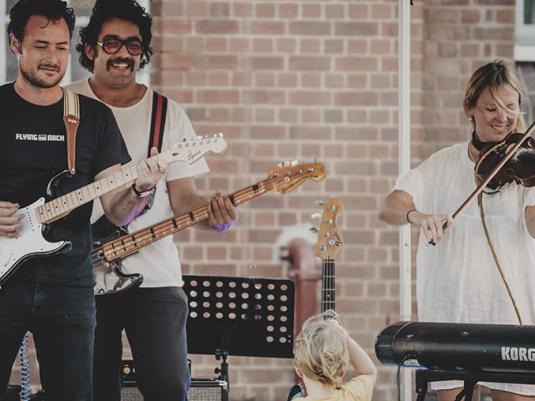A band playing live, smiling at a young child in the audience