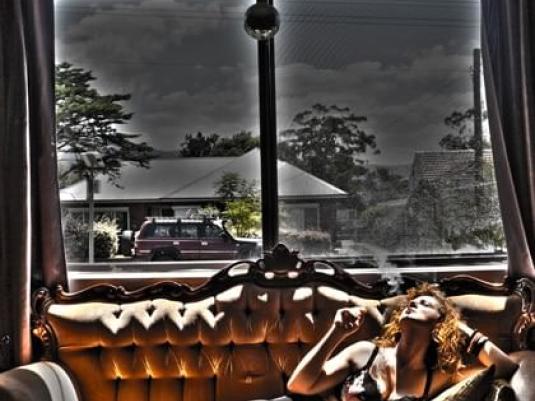 woman reclining on couch in front of window with street scene outside