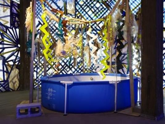 swimming pool with jungle themed background constructed with found objects