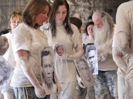 peple coveredin mud holding photographic portraits of people lost in volcano diaster