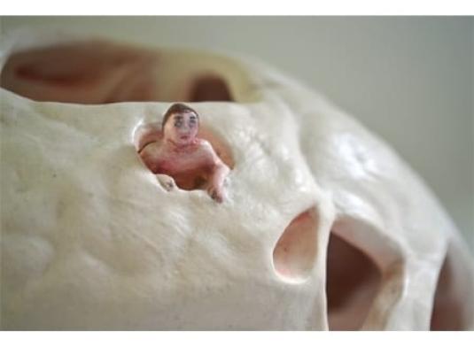 sculpture of person looking out of a hole in a ceramic form with holes