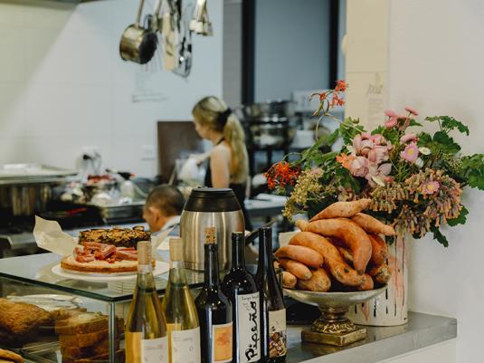 A busy cafe scene, looking from the counter into the kitchen