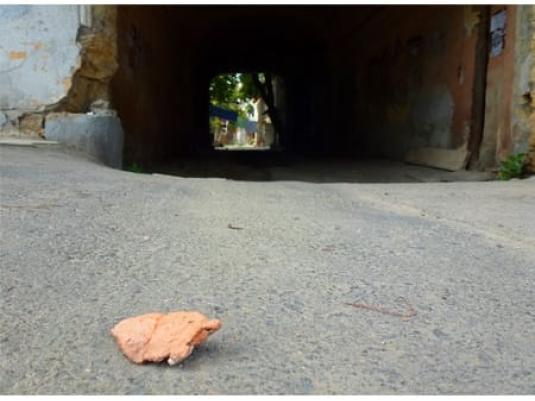 stone in foreground of photo with an archway showing light at end of tunnel in background