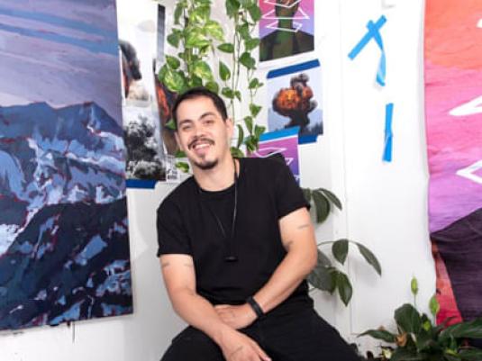 Abdul Abdullah sitting in front of artworks and plants