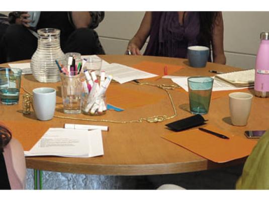 people at table with writing materials and drinking cups