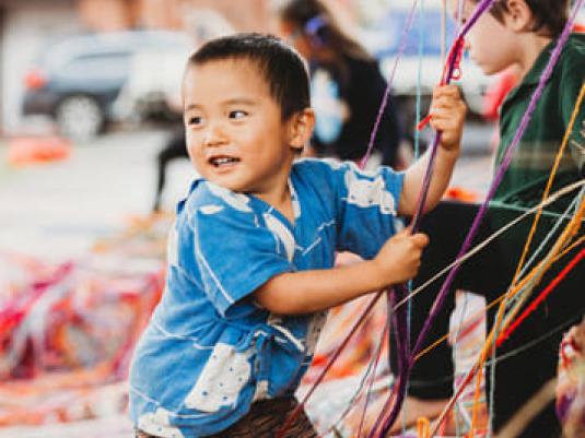 young child playing with coloured strings