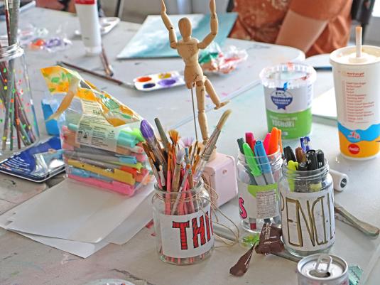 A table with art and craft materials like paints, pencils and paper