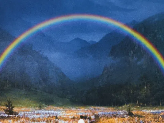 A poster for the film 'Dreams', a glorious scene of blue sky with a huge rainbow in front of mountain peaks, with fields full of flowers and a child in Japanese traditional dress looking out